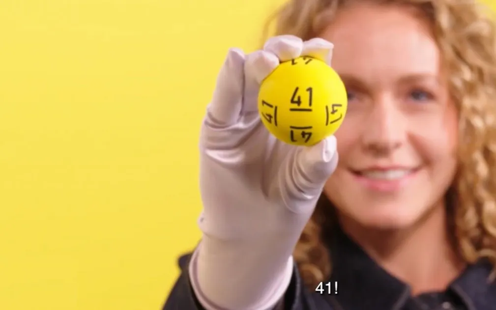 Gele bal met het nummer 41, gehouden door een persoon met een witte handschoen.