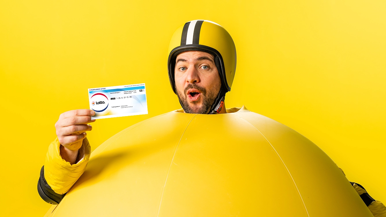 Persoon in gele outfit houdt een Lotto-lot vast tegen een gele achtergrond.