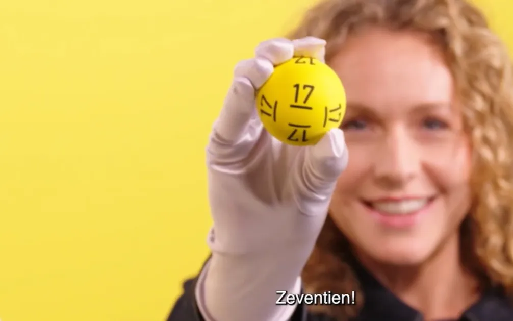 Persoon houdt een gele bal met het nummer 17 omhoog.