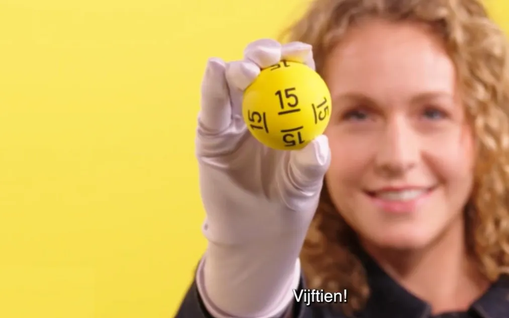 Een hand met een gele bal met het nummer 15, achtergrond in het geel.